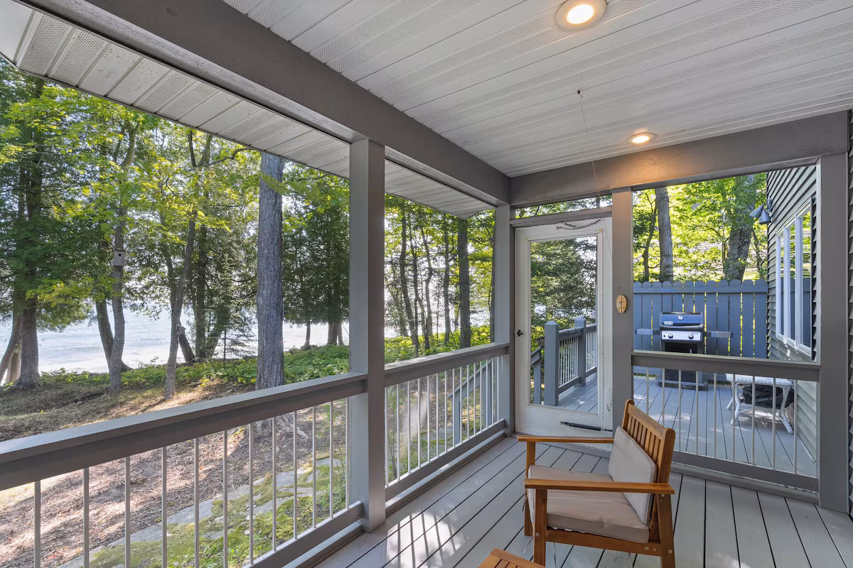Screened porch overlooking the lake through mature trees